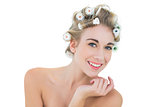 Pleased blonde model in hair curlers looking at camera