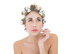 Thoughtful blonde model in hair curlers looking up