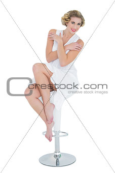 Content fashion blonde model posing sitting on bar chair