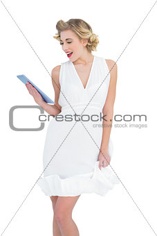 Delighted fashion blonde model looking at a tablet pc