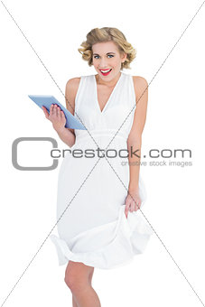 Amused fashion blonde model holding a tablet pc