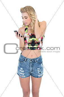 Pensive retro blonde model looking at her mobile phone