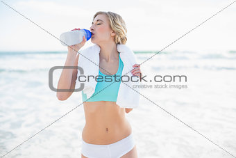 Relaxed blonde woman in sportswear drinking water