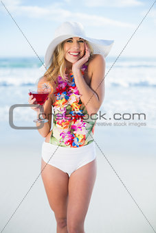 Pleased blonde model in swimsuit holding a cocktail