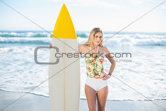 Pretty blonde model in swimsuit holding a surfboard