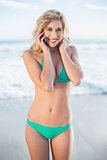 Amused blonde woman in green bikini calling with her mobile phone