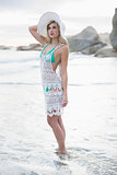 Thinking blonde woman in white beach dress posing looking away