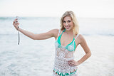Joyful blonde woman in white beach dress taking a picture of herself