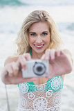Amused blonde woman in beach dress taking a picture