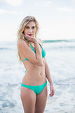 Cute blonde woman in green bikini posing holding her head
