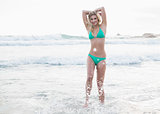 Happy blonde woman in green bikini posing looking at camera