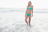Thinking blonde woman in green bikini walking