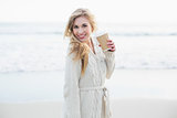 Happy blonde woman in wool cardigan enjoying coffee