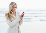 Pleased blonde woman in wool cardigan using a mobile phone