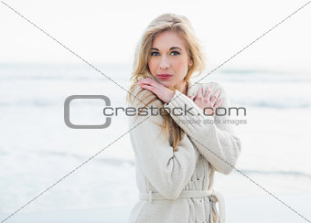 Pensive blonde woman in wool cardigan looking at camera