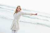 Amused blonde woman in wool cardigan stretching her arms