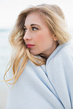 Stylish blonde woman covering herself in a blanket