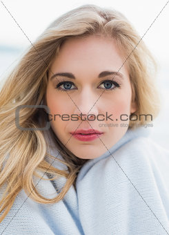 Lovely blonde woman covering herself in a blanket