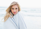 Thoughtful blonde woman covering herself in a blanket
