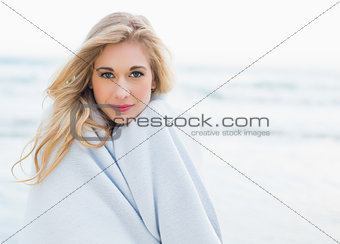 Thoughtful blonde woman covering herself in a blanket