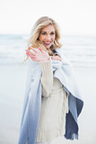 Happy blonde woman in a blanket waving at the camera