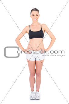 Smiling woman in sportswear hands on hips looking at camera