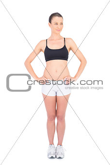 Fit woman in sportswear and hands on hips looking away