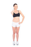 Fit smiling woman in sportswear giving thumbs up at camera
