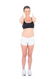 Positive fit woman in sportswear giving thumbs up and smiling at camera