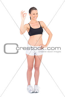 Portrait of happy woman in sportswear making okay gesture