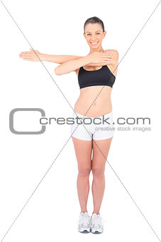 Smiling woman in sportswear stretching looking at camera