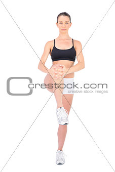 Serious woman in sportswear stretching her leg