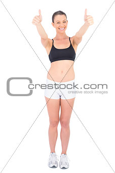 Cheerful woman in sportswear giving thumbs up to camera