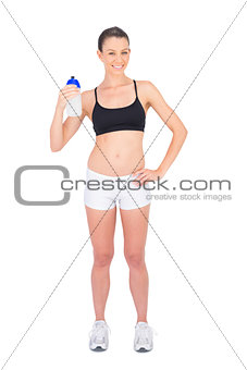 Smiling woman in sportswear holding flask