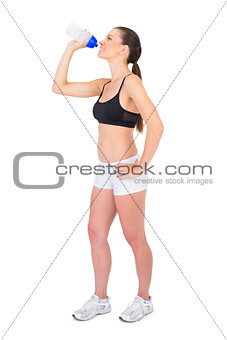 Smiling fit woman in sportswear drinking water