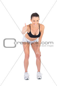 Smiling fit model in sportswear giving thumb up to camera