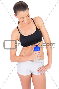 Happy toned woman in sportswear holding flask