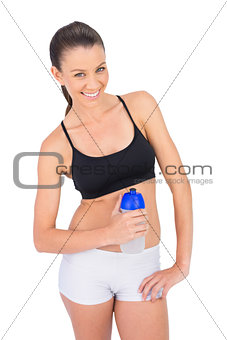 Smiling toned woman in sportswear holding flask