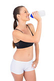 Smiling toned woman in sportswear drinking water