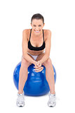 Smiling fit woman in sportswear sitting on exercise ball