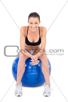 Smiling fit woman in sportswear sitting on exercise ball