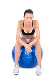 Serious fit woman sitting on exercise ball