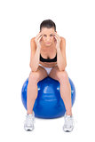 Worried fit woman sitting on exercise ball
