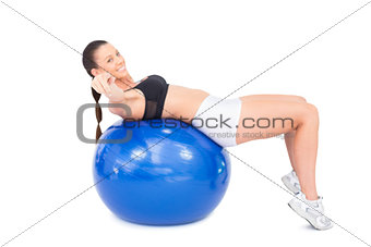 Smiling sporty woman working out with exercise ball pointing at camera
