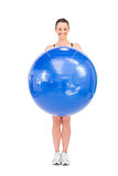 Happy fit woman holding exercise ball in front of her
