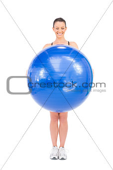Happy fit woman holding exercise ball in front of her