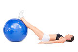 Side view of fit woman lying working out with exercise ball