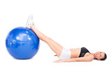 Side view of relaxed fit woman lying working out with exercise ball
