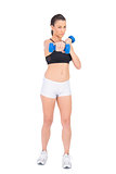 Serious fit woman working out with dumbbells