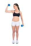 Relaxed fit woman exercising with dumbbells